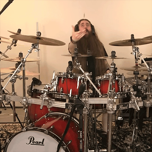 A Man Playing Drums With A Pearl Drum Set In The Foreground GIF
