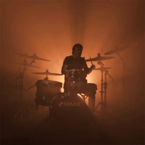 A Man Playing Drums With A Sonor Drum Set In The Foreground GIF