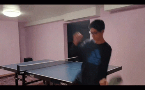 A Man Playing Ping Pong With A Joola Table In The Background GIF