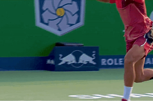 A Man Playing Tennis In Front Of A Red Bull Sign GIF