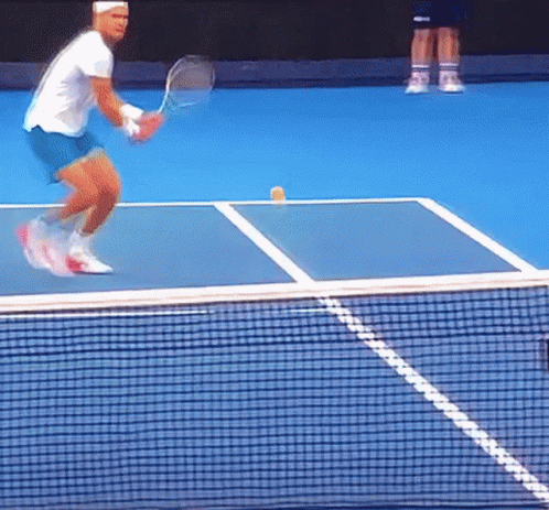 a man playing tennis on a blue court with a yellow ball on the court