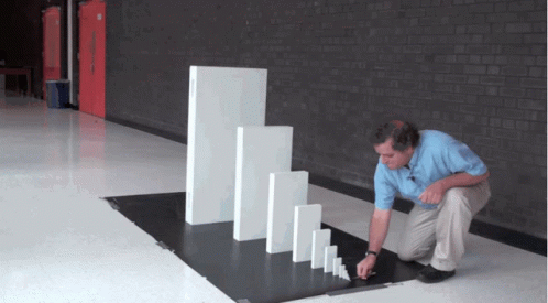 A Man Playing With Dominoes In A Hallway With A Brick Wall GIF