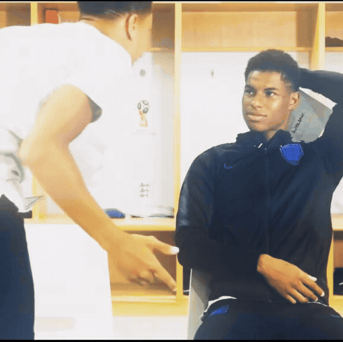 A Man Pointing At Another Man In A Locker Room That Says ' England ' On The Wall GIF