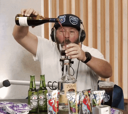 A Man Pouring A Drink Into A Glass From A Bottle Of Tito 'S GIF