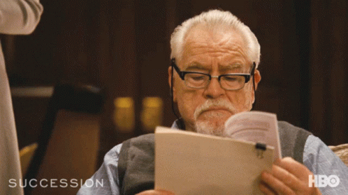 A Man Reading A Book With The Word Succession On The Bottom Left GIF