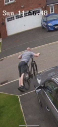 A Man Riding A Bike Next To A Car On A Sunny Day With The Time Of 11:56 GIF