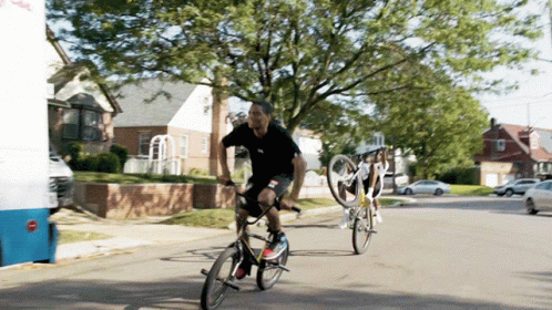 A Man Riding A Bike On A Street Next To A White Van That Says ' Ice Cream ' On It GIF