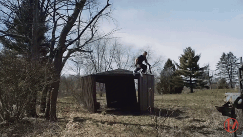A Man Riding A Bike On Top Of A Wooden Structure In A Field GIF