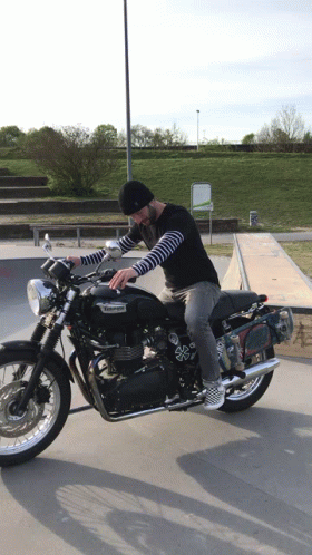 A Man Riding A Black Triumph Motorcycle In A Skatepark GIF