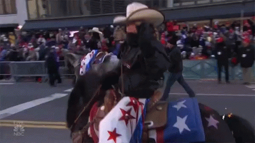 A Man Riding A Horse In A Parade With A Merry Thanksgiving Star GIF