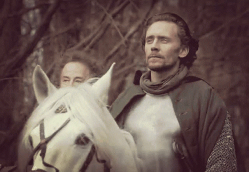 A Man Riding A White Horse With Another Man Standing Behind Him GIF