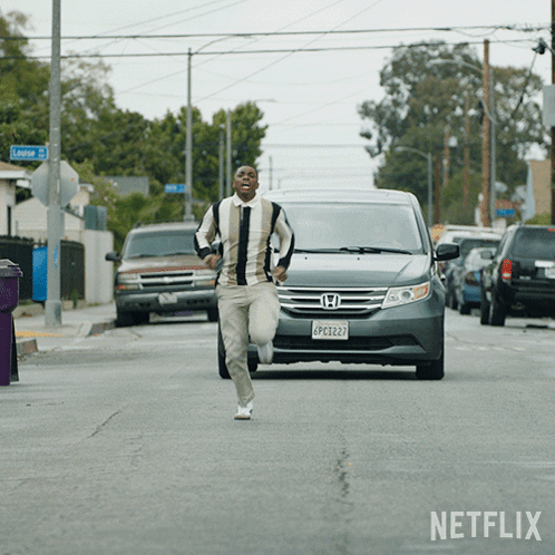 A Man Running Down A Street In Front Of A Netflix Ad GIF