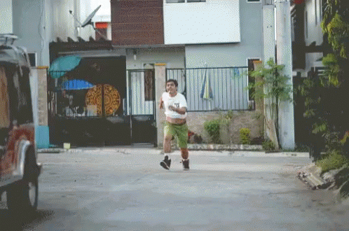 A Man Running Down A Street With A Pizza On The Fence In The Background GIF