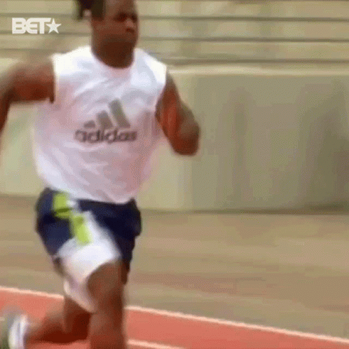 A Man Running On A Track Wearing A White Adidas Tank Top GIF