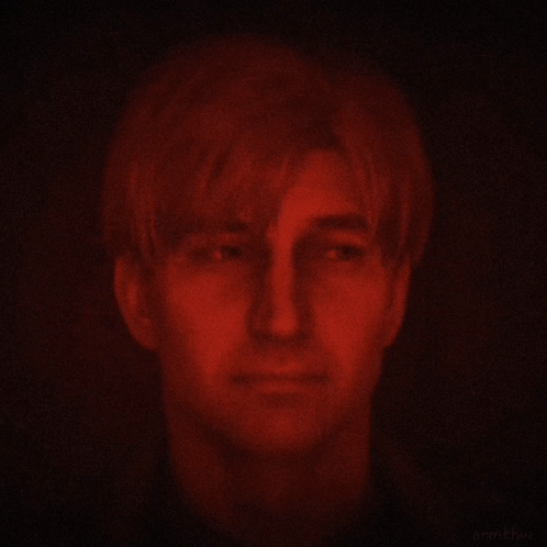 A Man 'S Face Is Glowing Red In The Dark GIF
