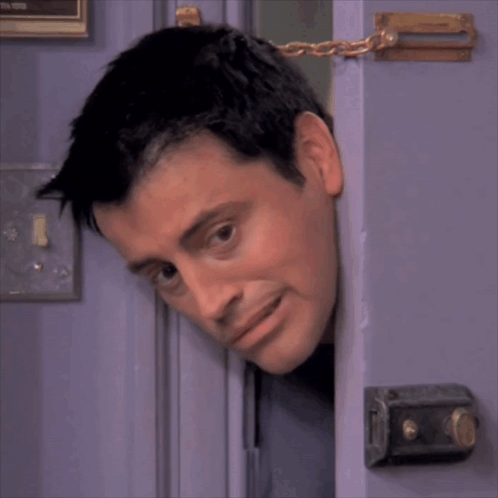 A Man 'S Head Is Sticking Out Of A Door With A Chain Around It GIF