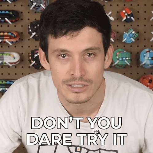 A Man Says " Don T You Dare Try It " In Front Of A Wall Of Toy Cars GIF