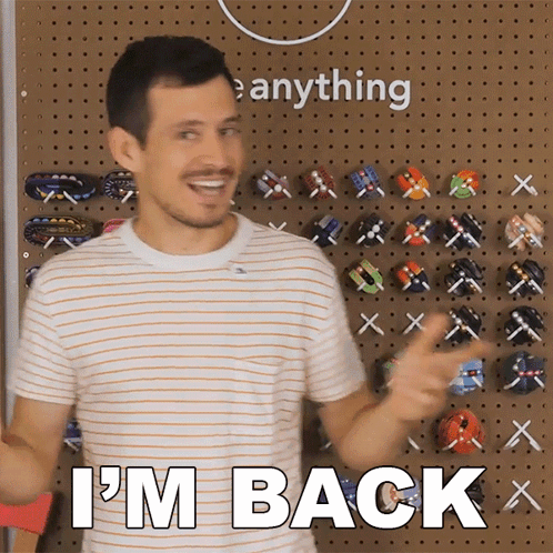 A Man Says I 'M Back In Front Of A Wall Of Toys GIF