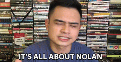 A Man Says It 'S All About Nolan In Front Of A Stack Of Books GIF