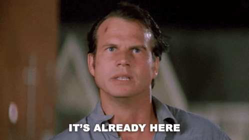 A Man Says " It 'S Already Here " In Front Of A Dark Background GIF