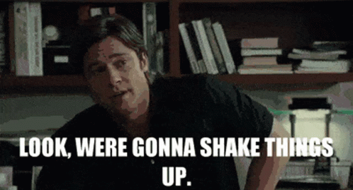 A Man Says Look Were Gonna Shake Things Up In Front Of A Bookshelf GIF