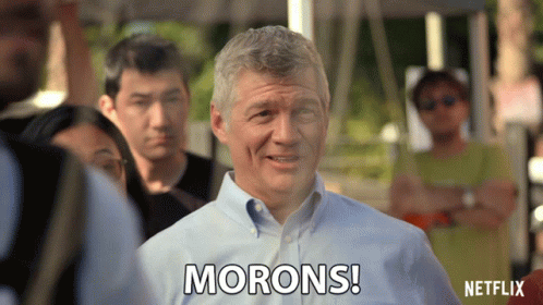 A Man Says Morons While Standing In A Crowd GIF