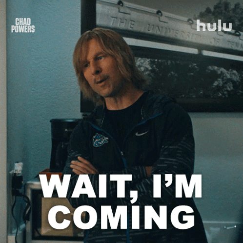 A Man Says Wait I 'M Coming In Front Of A Sign That Says Hulu GIF