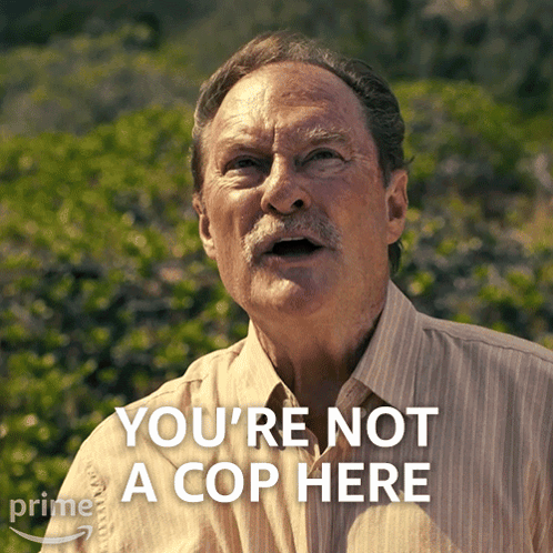 A Man Says " You 'Re Not A Cop Here " In Front Of Some Bushes GIF