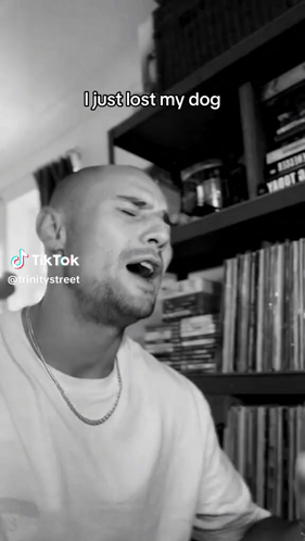 A Man Singing In Front Of A Bookshelf That Says I Just Lost My Dog On It GIF