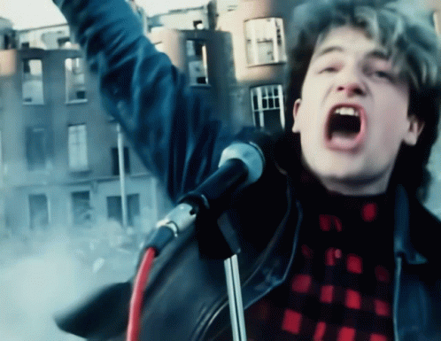 a man singing into a microphone in front of a building