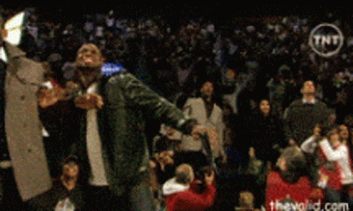 a man singing into a microphone in front of a crowd with a tnt logo in the corner