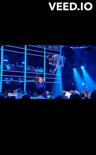 A Man Singing Into A Microphone In Front Of A Crowd With The Words " Veed.io " At The Top GIF