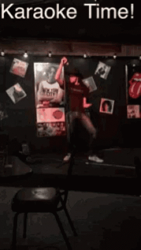 a man singing into a microphone in front of a sign that says karaoke time !