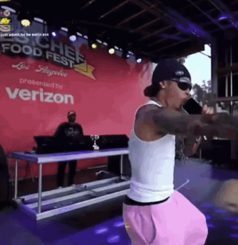 A Man Singing Into A Microphone In Front Of A Verizon Sign GIF