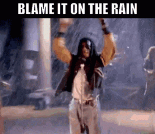 A Man Singing Into A Microphone In The Rain With The Words Blame It On The Rain Below Him . GIF