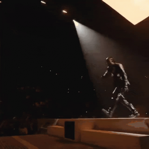 A Man Singing Into A Microphone On A Stage GIF