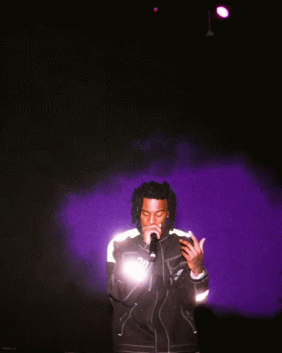 A Man Singing Into A Microphone Wearing A Jacket That Says ' Dg ' On It GIF