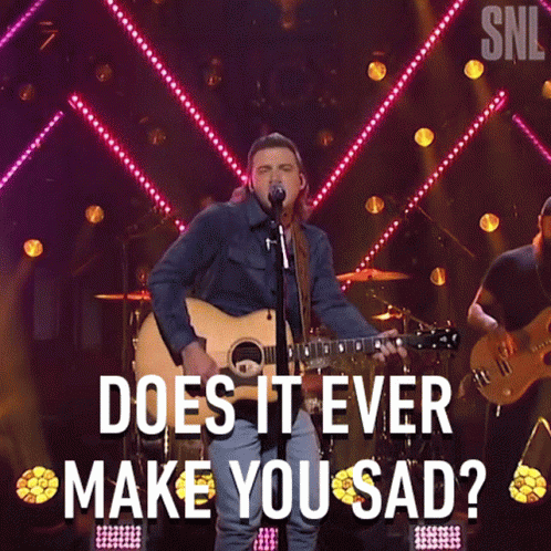 A Man Singing Into A Microphone While Holding A Guitar With The Words " Does It Ever Make You Sad " Above Him GIF