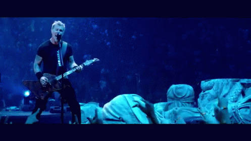 A Man Singing Into A Microphone While Playing A Guitar In Front Of A Crowd GIF
