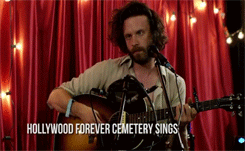a man singing into a microphone while playing a guitar with the words hollywood forever cemetery sings written below him