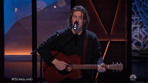 A Man Singing Into A Microphone While Playing A Guitar With The Words Songland On The Bottom Right GIF