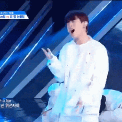 A Man Singing Into A Microphone While Wearing A White Shirt GIF