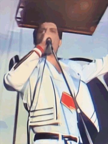 A Man Singing Into A Microphone While Wearing A White Shirt GIF