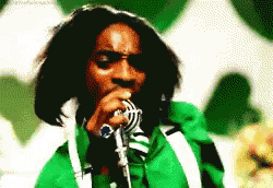A Man Singing Into A Microphone With A Green Jacket On GIF