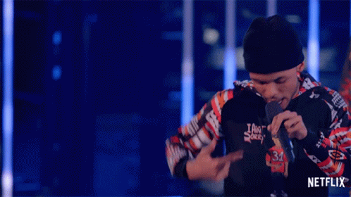 A Man Singing Into A Microphone With A Netflix Logo On The Bottom Right GIF