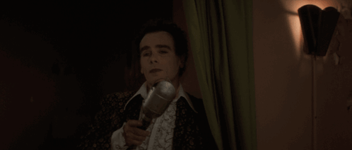 A Man Singing Into A Microphone With His Mouth Open GIF