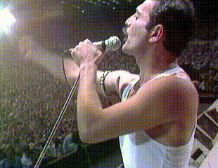 A Man Singing Into A Microphone With His Mouth Open GIF