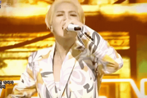 A Man Singing Into A Microphone With Korean Writing On The Screen GIF