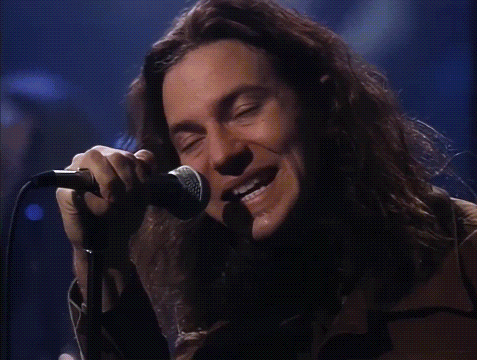a man singing into a microphone with the words he looks insane behind him