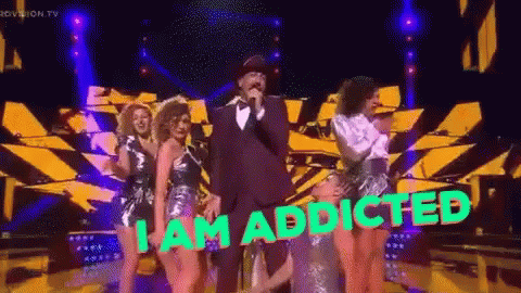 A Man Singing Into A Microphone With The Words " I Am Addicted " On The Bottom GIF